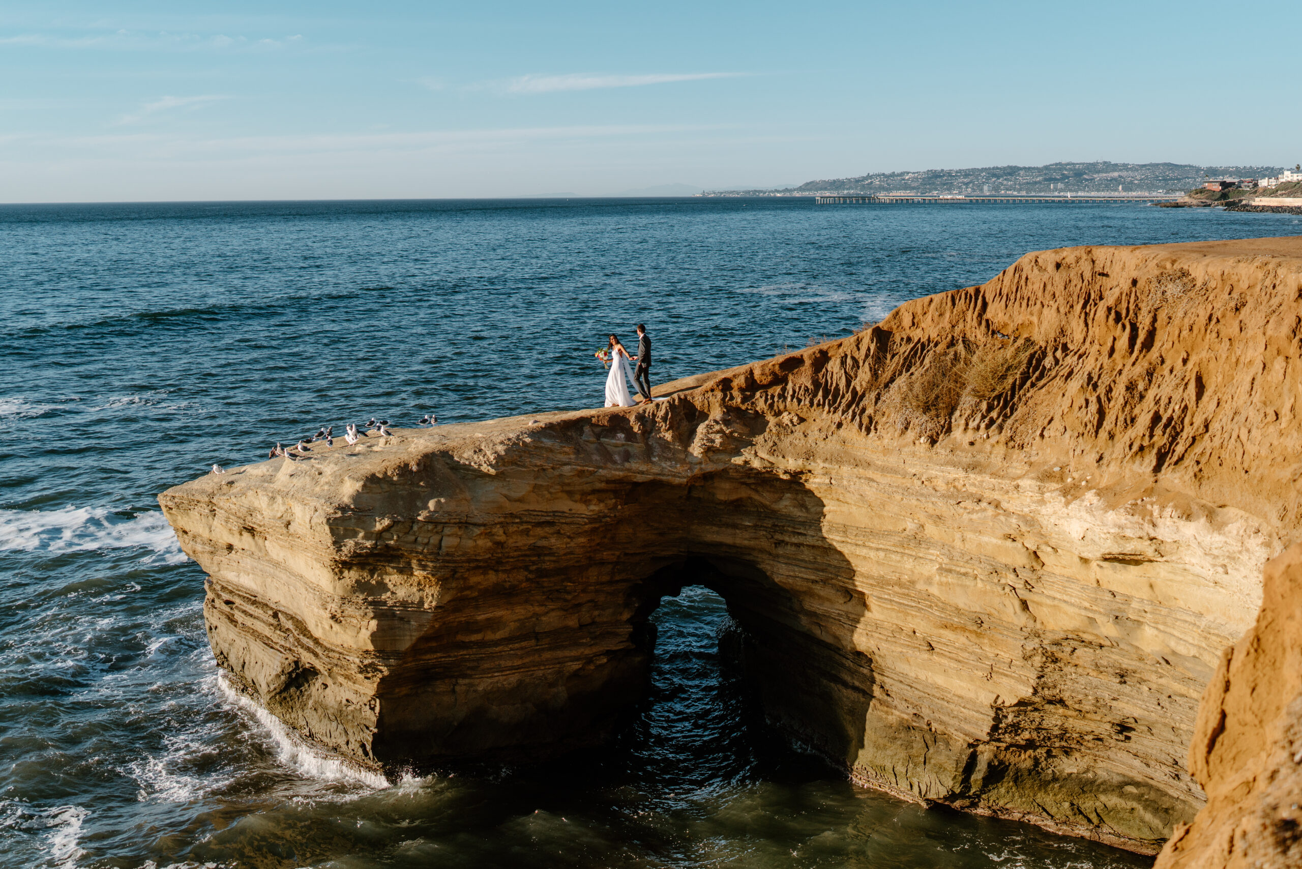 Bride and groom on ocean cliff