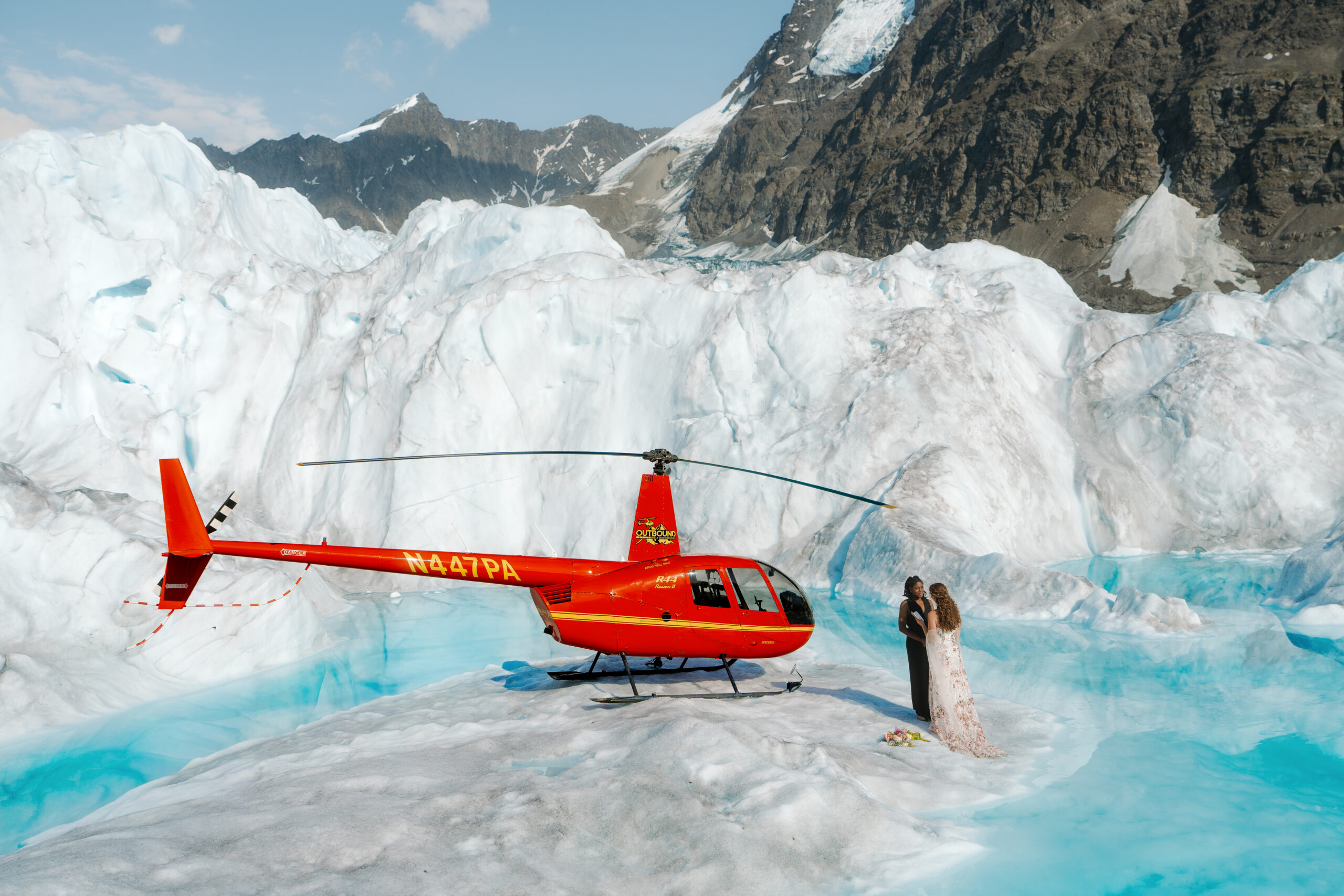 Couple exchanging vows on a glacier in Alaska next to a helicopter